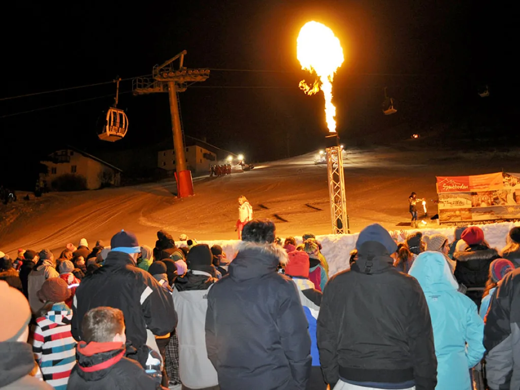 Feuersäule bei der Abendveranstaltung, davor die Zuschauer.